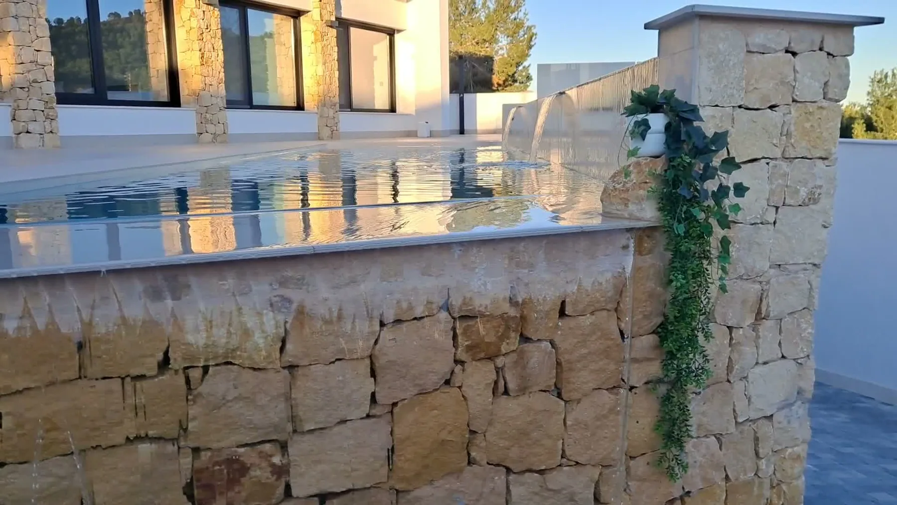 Piscina desbordante elevada con revestimiento de piedra