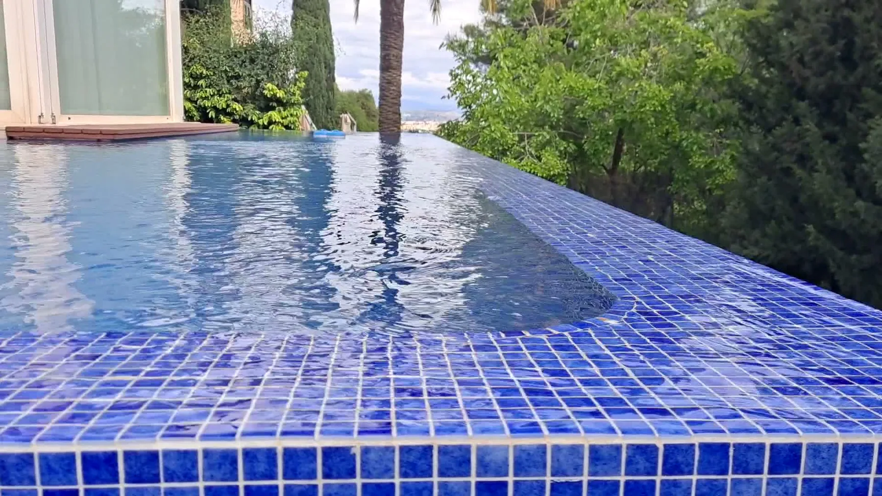 Piscina infinity revestida con mosaico azul