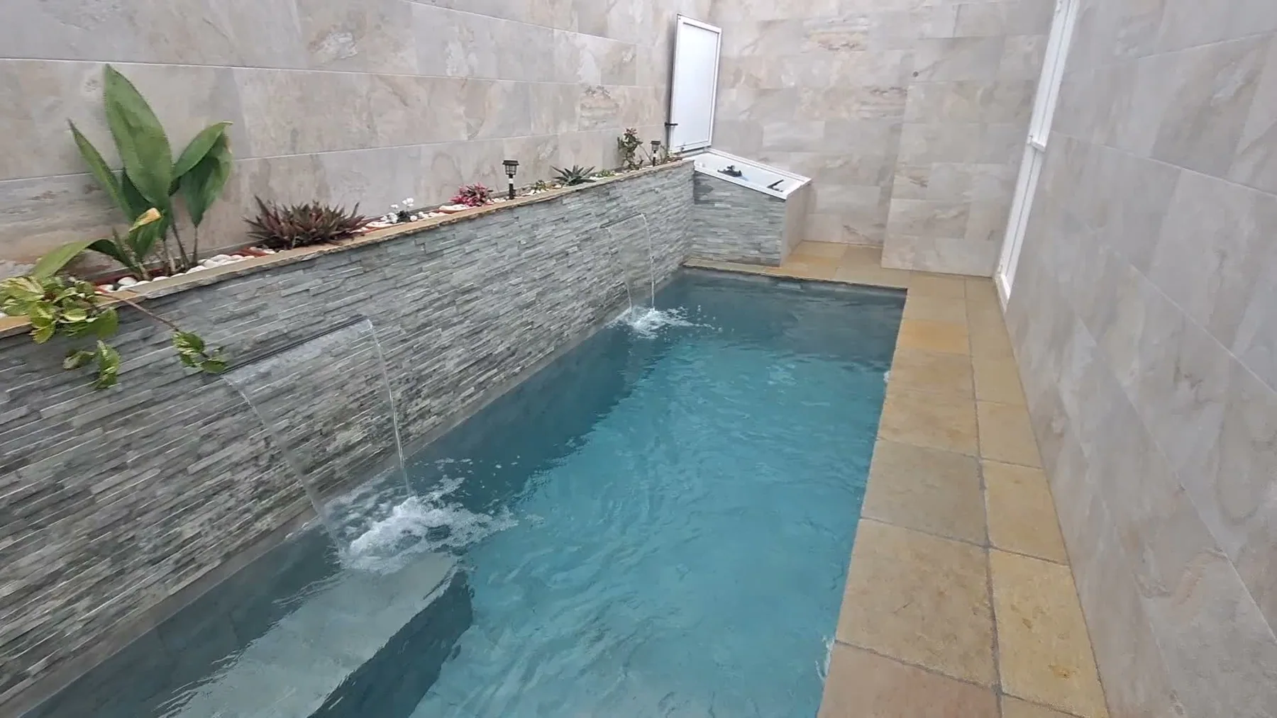 Piscina compacta con cascadas de pared