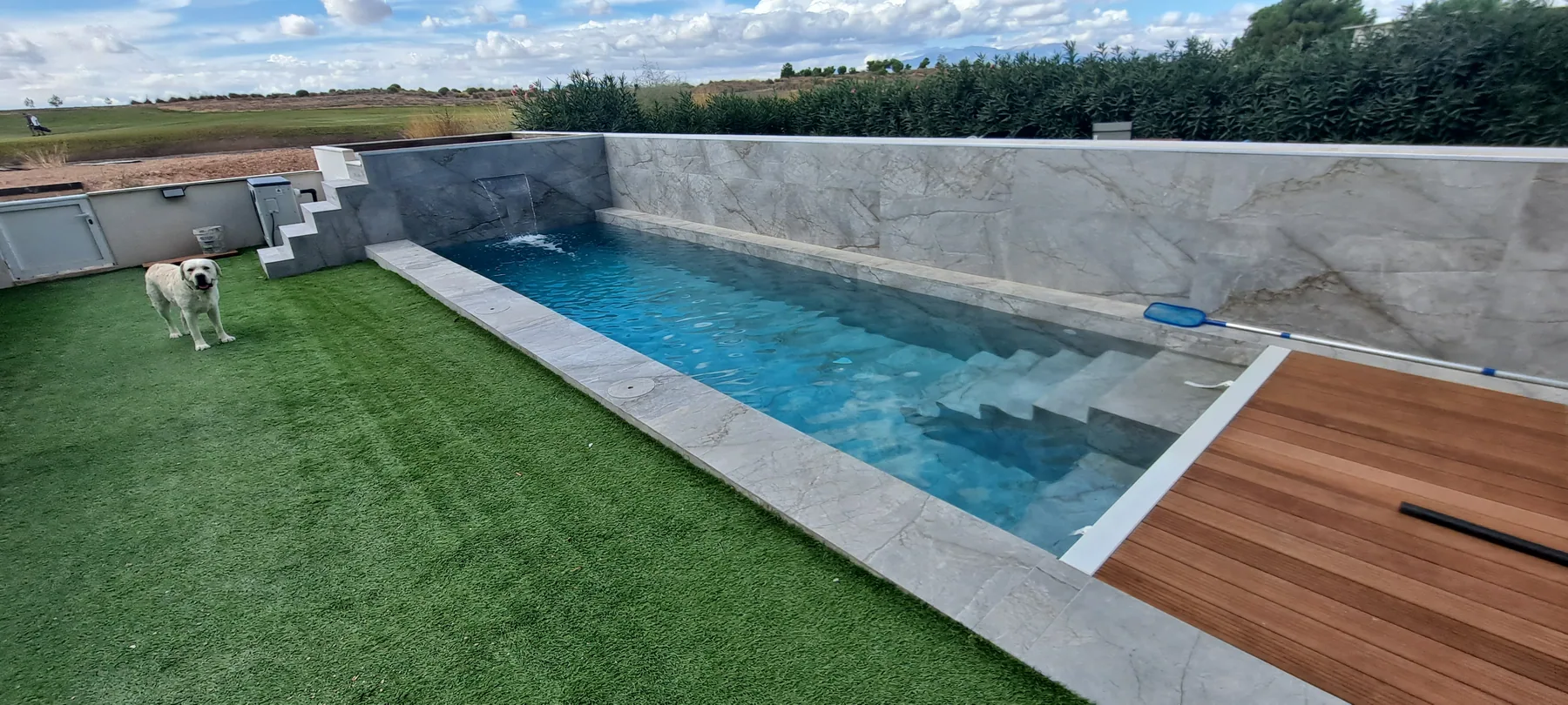 Piscina de obra integrada en jardín con tarima